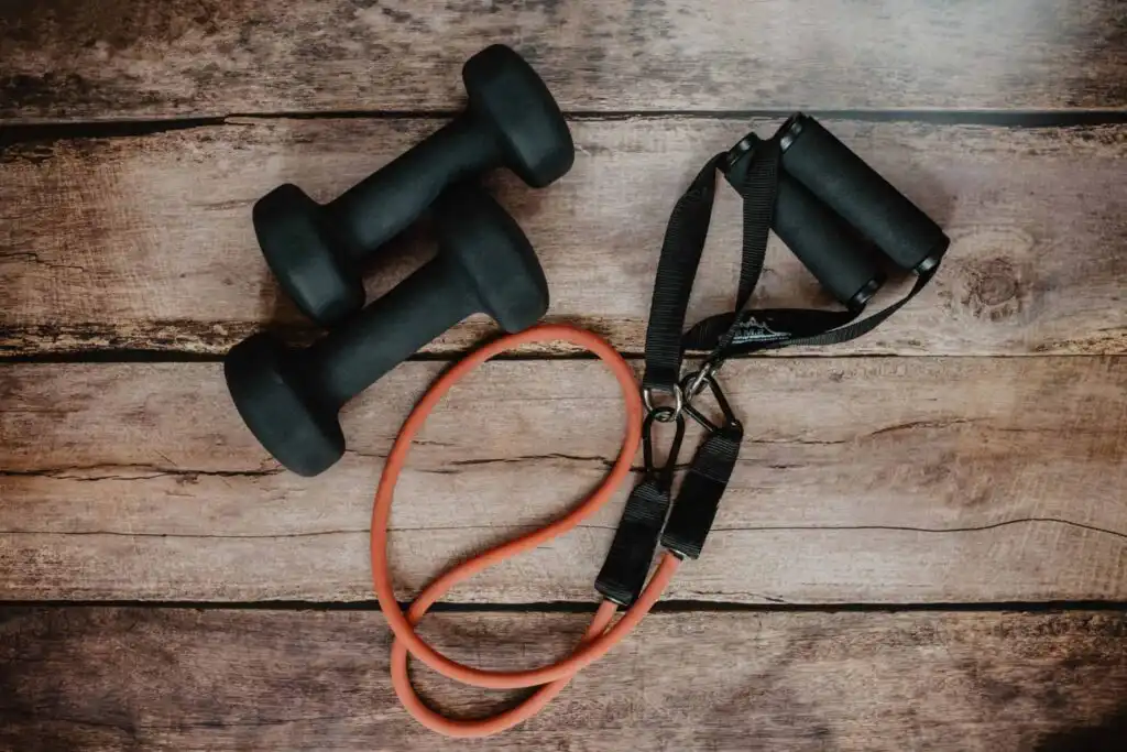Sedentary lifestyle negates your exercise class 1 black hand weights and a resistance band against a wooden board background