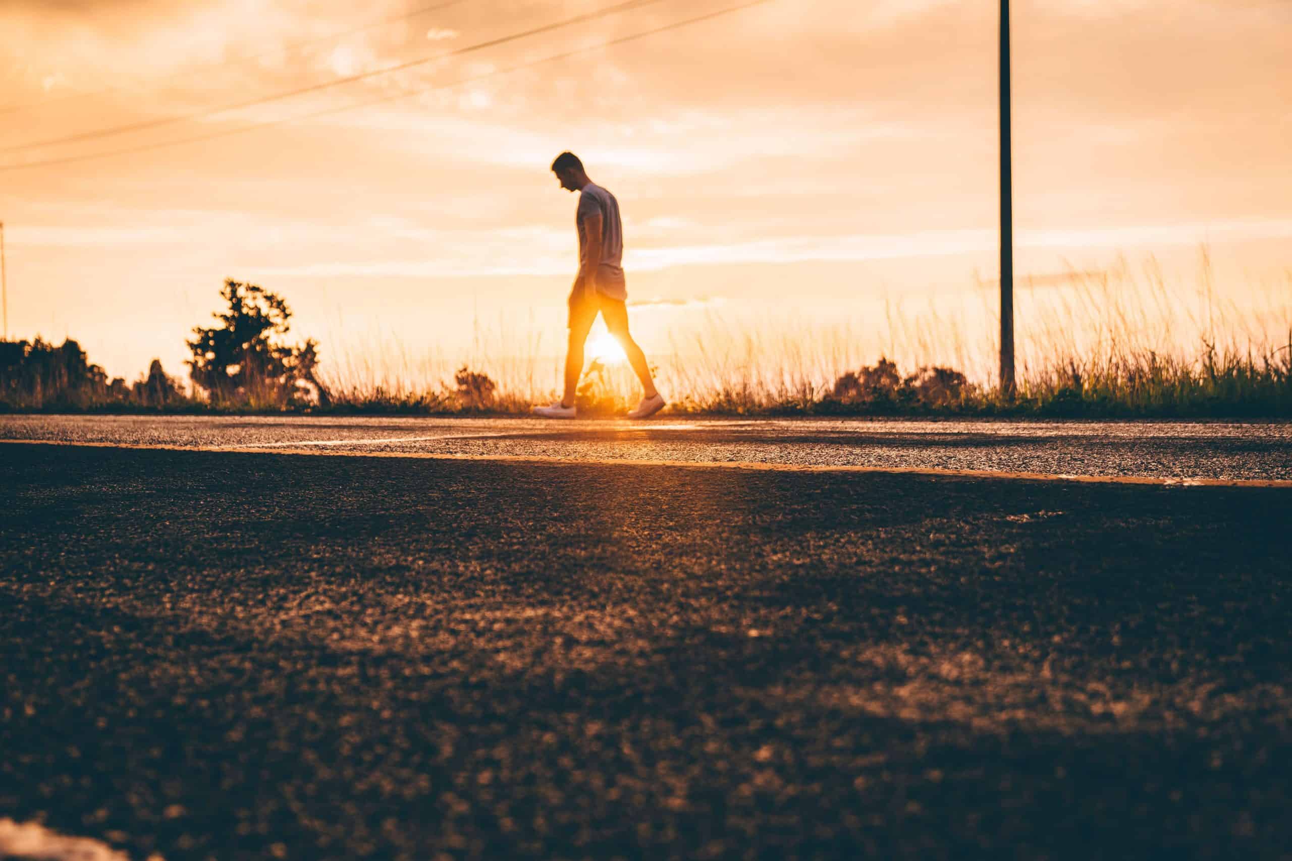 a man walking against a sunrise