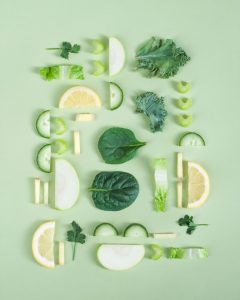 flat lay with spinach, cucumber, pear, lemon and celery