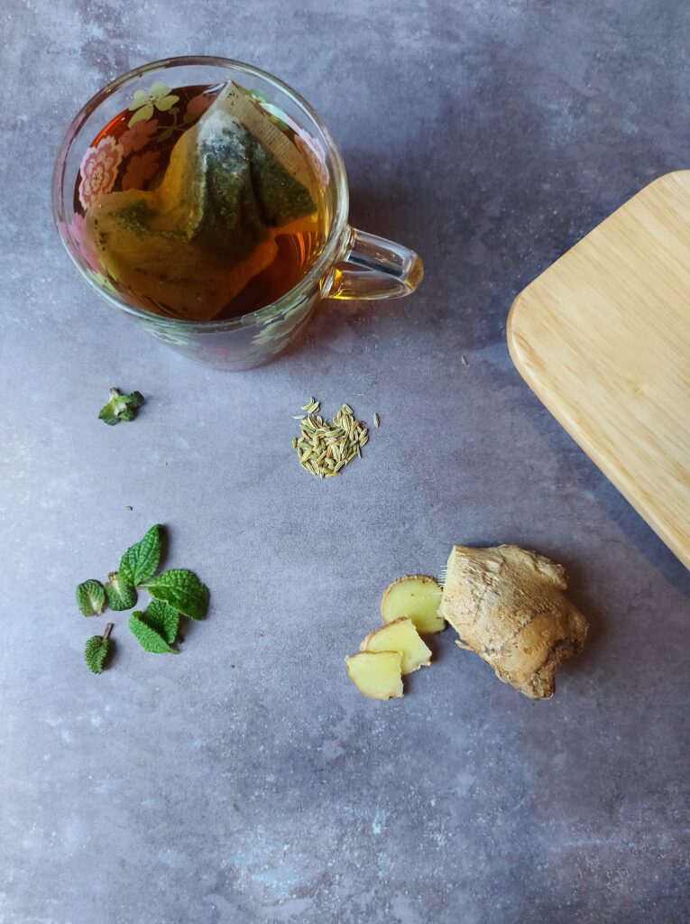 Best Herb Teas for IBS 3 herb tea on a grey background with some cut ginger next to it, and fennel seeds.