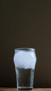 glass of water with ice, against a black background