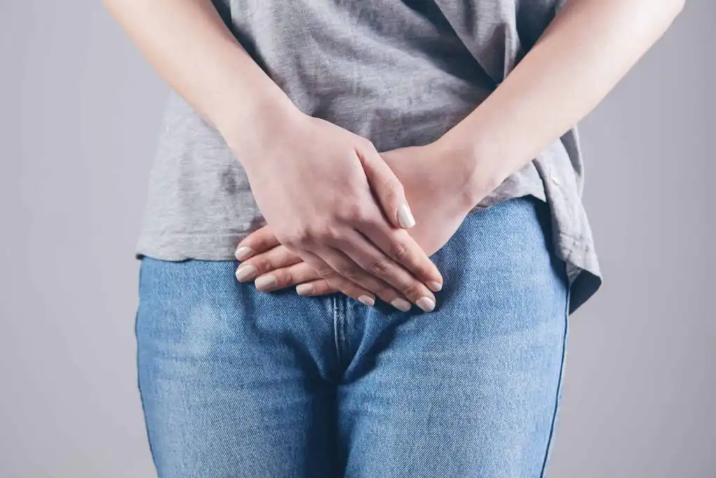 Why does my stomach rumble? Causes of noisy digestion 2 white person wearing grey t shirt and jeans hands crossed over intestines