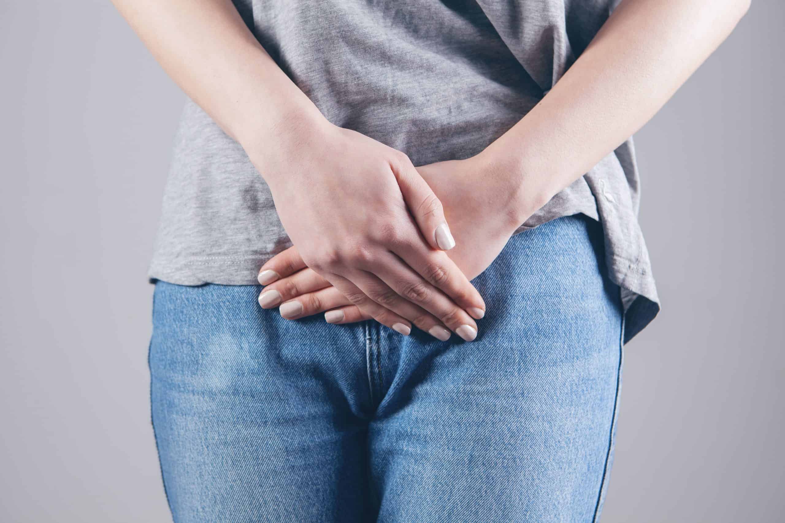 white person wearing grey t shirt and jeans hands crossed over intestines