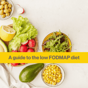 A white table laid with round bowls of high and low FODMAP foods, including a bowl of sweetcorn, a bowl of mixed lettuce, a bowl of green olives and a whole avocado