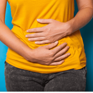 white woman torso with hands holding stomach for constipation