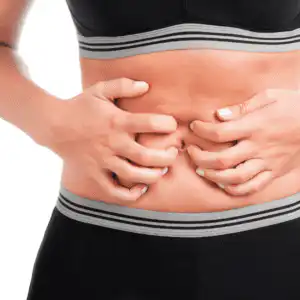 why do my farts smell bad (1) close up of a white person's hand clutching bare stomach, black leggings and crop top