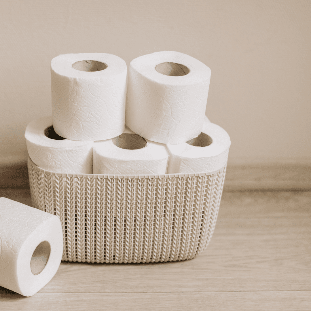 stack of toilet rolls in a wicker basket against beige background