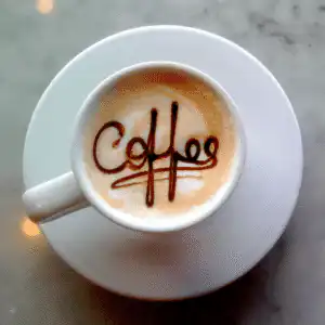 white coffee cup and saucer, Coffee written in the coffee froth with dark brown