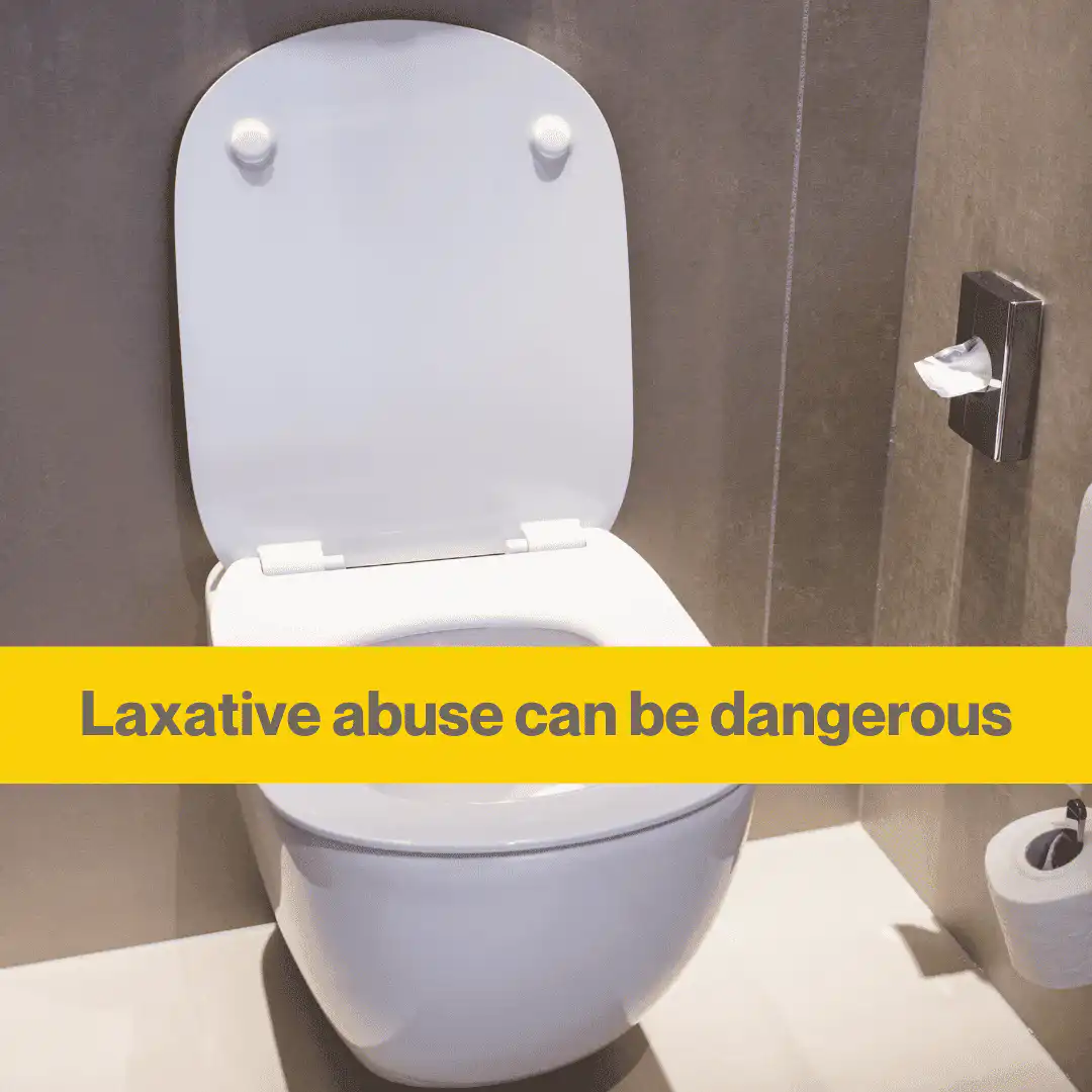 A white toilet in a grey bathroom. A yellow banner with the words Laxative abuse can be dangerous.