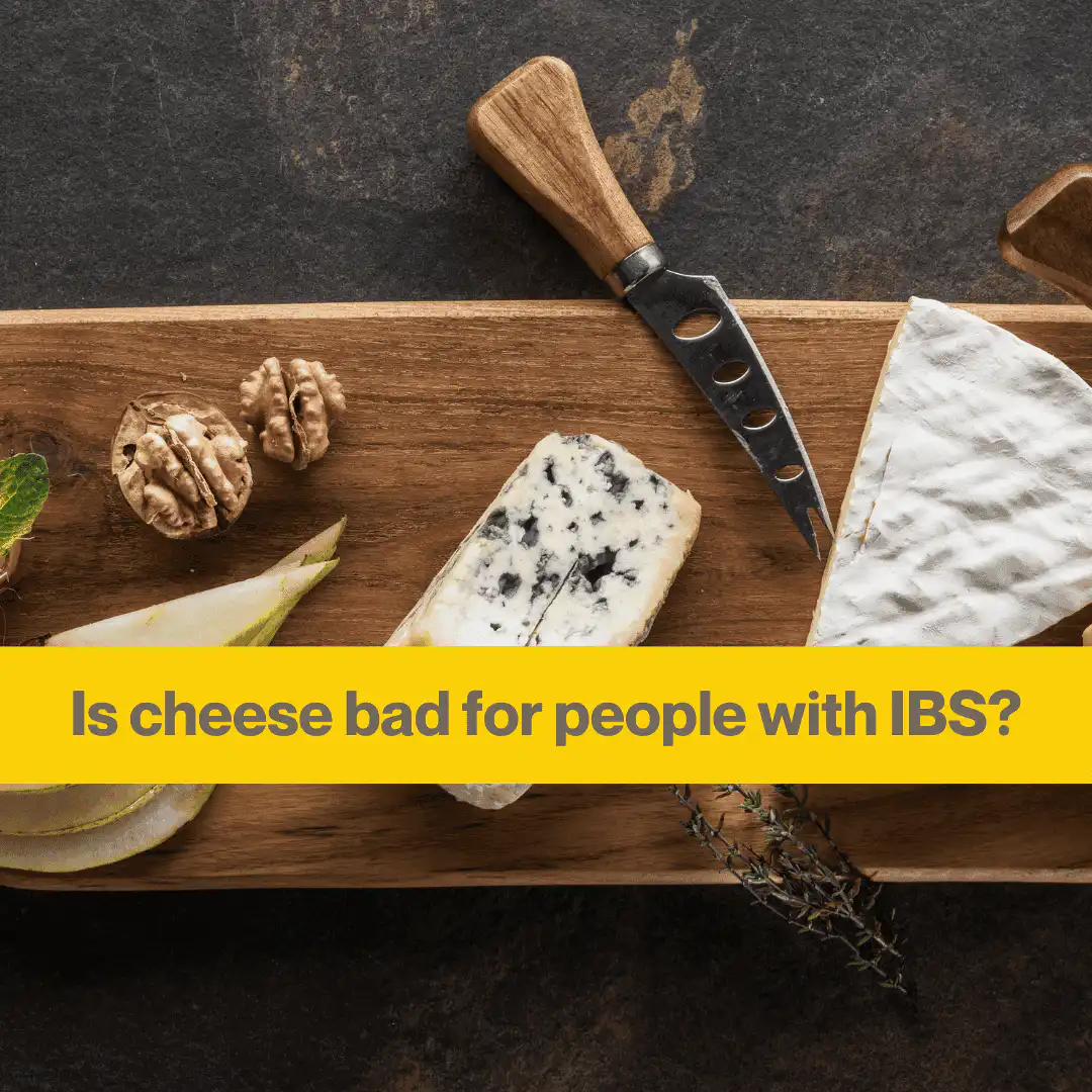 Dark background, wooden board with a triangular piece of brie, a wedge of blue cheese and a cheese knife. Two walnuts halfs, and the words Is cheese bad for people with IBS