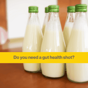 5 glass bottles of yoghurt in a cluster on a dark wooden table. Bottles have green screw on lids. 