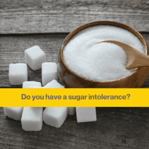 Wooden background with a bowl of sugar in a small wooden bowl and some sugar cubes on the table