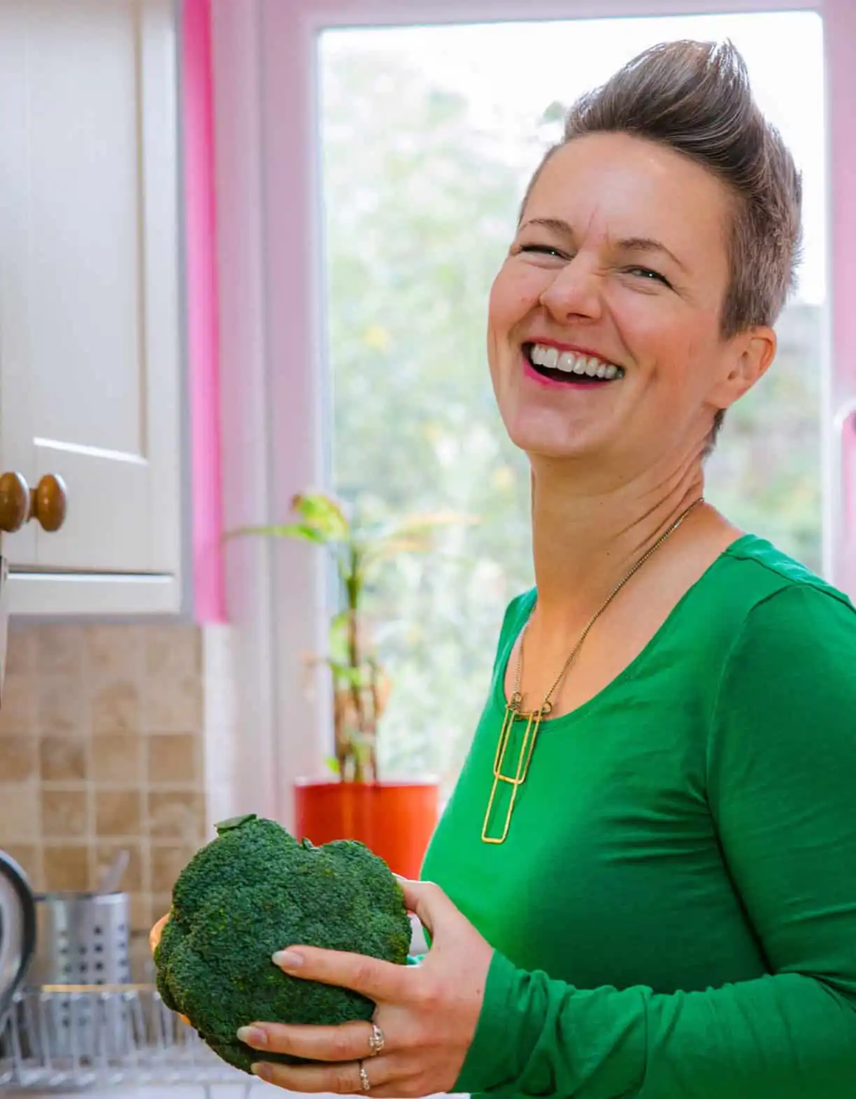 Nutritionist reviewing a meal plan with a man seated at a table, with fruits, a clipboard, and healthy food items visible in a bright kitchen setting.