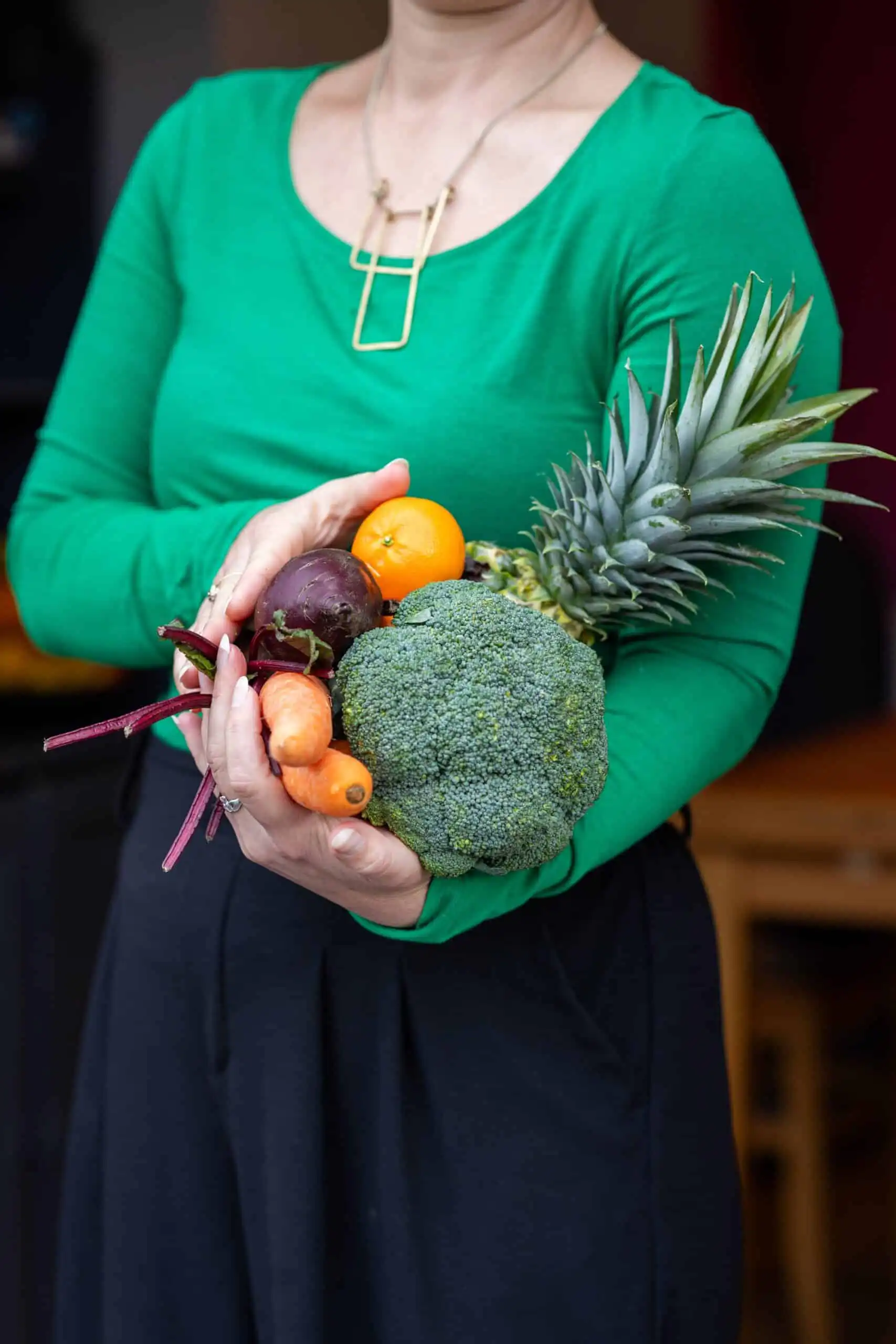 Nutritionist reviewing a meal plan with a man seated at a table, with fruits, a clipboard, and healthy food items visible in a bright kitchen setting.